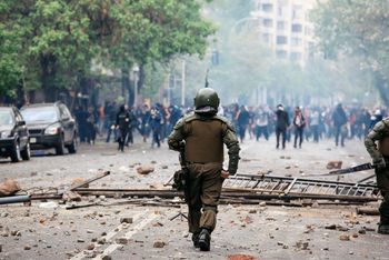 Close up of police officer dealing with rioters in distance