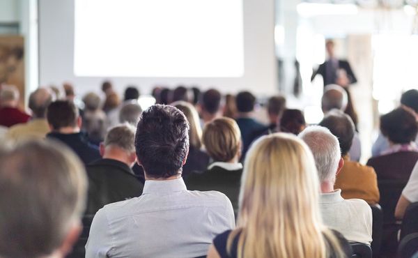 People in a meeting back of heads from back of room sharp focus on foreground