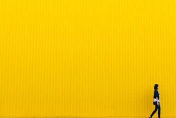 Woman in black top standing near a yellow wall