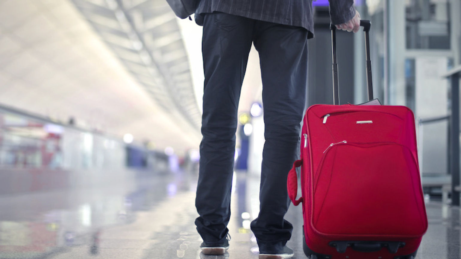 business traveller at airport red suitcase