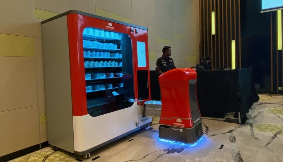 Conference demo: INTERLOCK GROUP’S Alyx, the delivery robot (right) removing a towel from Lily, the vending machine.