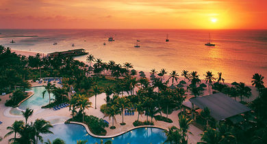 The beachfront pool at sunset at the Hilton Aruba Caribbean Resort & Casino Marble facade: Interior of the  Columbus Lighthouse (Faro a Colon).
