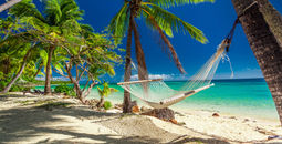 Empty hammock in the shade of palm trees on tropical Fiji Islands (photo via mvaligursky / iStock / Getty Images Plus)
