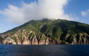 The caribic Island of Saba with on top of vulcano Mount Scenery a cloud (photo via steeric / iStock / Getty Images Plus)
