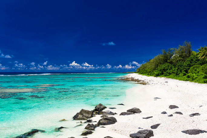 Amazing beach with white sand and black rocks on Rarotonga, Cook Islands (Photo via mvaligursky / iStock / Getty Images Plus)