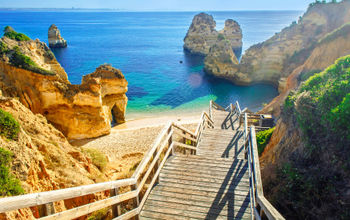 Wooden footbridge to beautiful beach Praia do Camilo near Lagos in algarve region, Portugal (Photo via samael334 / iStock / Getty Images Plus)