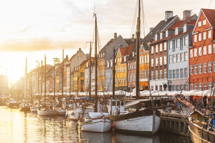 Colorful houses in Copenhagen old town at sunset Colorful houses in Copenhagen old town at sunset, with boats and ships in the canal in front of them. (photo via william87 / iStock / Getty Images Plus)