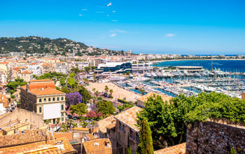 Top cityscape view on french riviera with yachts in Cannes city (Photo via  RossHelen / iStock / Getty Images Plus)