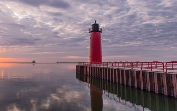 Red lighthouse on Lake Michigan at sunrise in Milwaukee, WI (photo via AMCImages / iStock / Getty Images Plus)