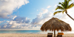 Beach chairs with umbrella and beautiful sand beach in Punta Cana, Dominican Republic (Photo via Preto_perola / iStock / Getty Images Plus)