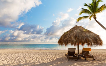 Beach chairs with umbrella and beautiful sand beach in Punta Cana, Dominican Republic (Photo via Preto_perola / iStock / Getty Images Plus)