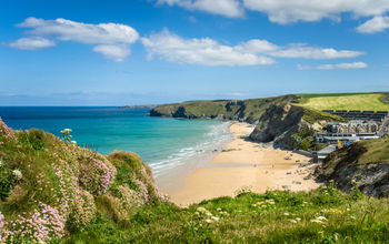 Photo of a Stretch of Coast in Cornwall with a Sandy Beach at the foot of high cliffs. (Photo via AlbertPego / iStock / Getty Images Plus)