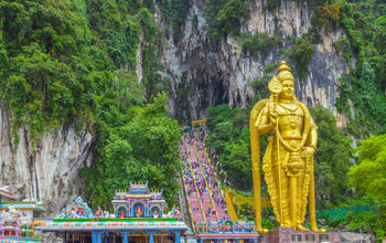Batu Caves Lord Murugan Statue and entrance near Kuala Lumpur Malaysia. A limestone outcrop located just north of Kuala Lumpur, Batu Caves has three main caves featuring temples and Hindu shrines. (photo via VladyslavDanilin / iStock / Getty Images Plus)