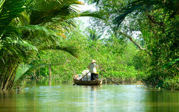 Woman driving a boat in the mekong delta. Vietnam. (photo via MasterLu / iStock / Getty Images Plus)