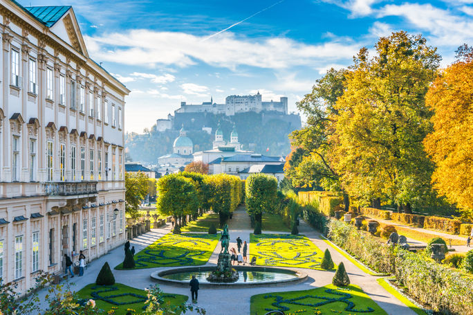 Beautiful view of famous Mirabell Gardens with the old historic Fortress Hohensalzburg in the background in Salzburg, Austria (photo via bluejayphoto / iStock / Getty Images Plus)