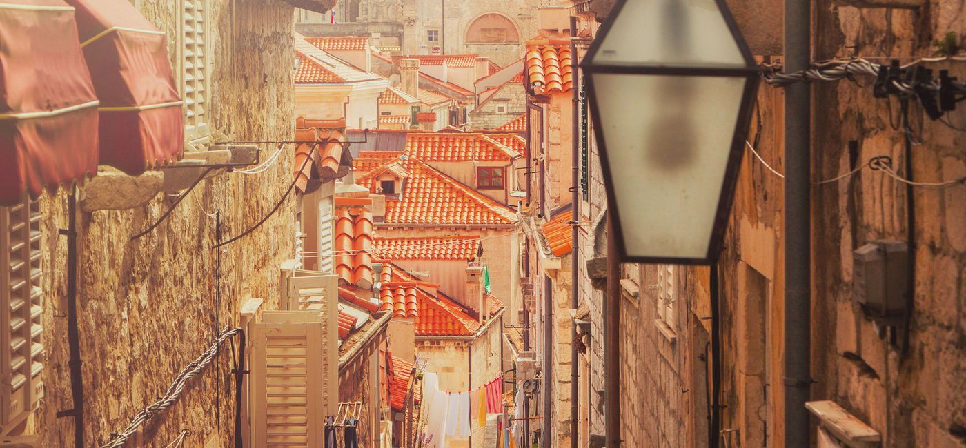 Image: Dubrovnik old city street view in Croatia, warm filter, lens flare (photo via iascic / iStock / Getty Images Plus)
