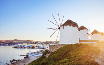 Windmills of Mykonos with blue sky and clouds. Mykonos, Greece. (JustinBlackStock / iStock / Getty Images Plus)