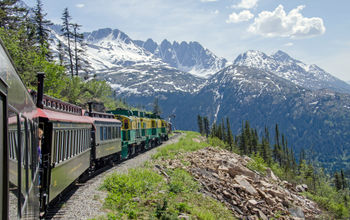 White Pass & Yukon Route Railroad travels along the cliffs heading towards Skagway, Alaska (photo via Chilkoot/iStock/Getty Images Plus)