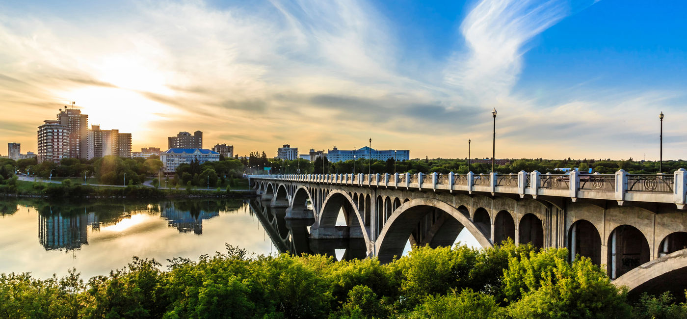 Image: A warm summer sunset over the city of Saskatoon located in Central Canada where the calm waters of the South Saskatchewan River flows under the University Bridge. (photo via sprokop / iStock / Getty Images Plus)