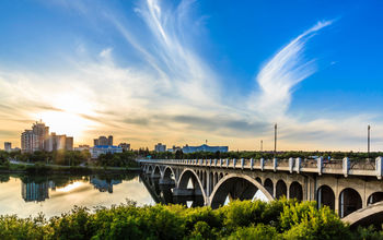 A warm summer sunset over the city of Saskatoon located in Central Canada where the calm waters of the South Saskatchewan River flows under the University Bridge. (photo via sprokop / iStock / Getty Images Plus)