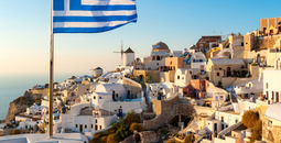 The Greek flag flying at sunset in the town of Oia in Santorini, Greece.