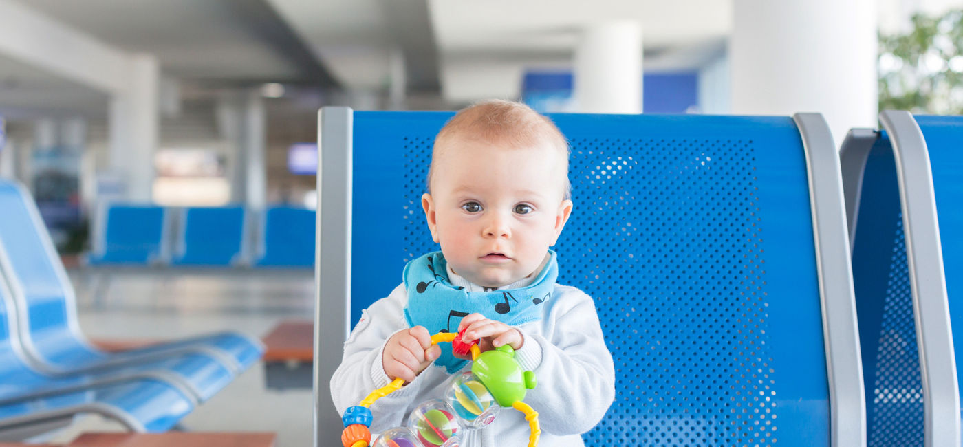 Image: An infant sitting in an airport waiting area. (photo via iStock/Getty Images Plus/tatyana_tomsickova)