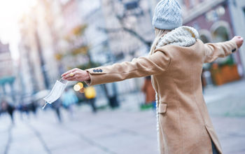 Woman taking off face mask in the city.