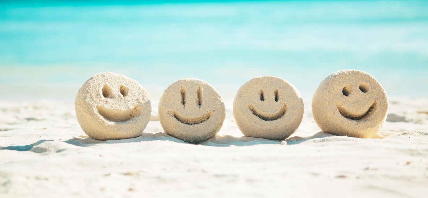 Image: PHOTO: Smiley faces in the sand (photo via danilovi / iStock / Getty Images Plus)
