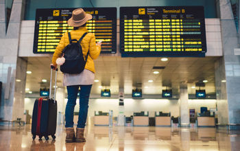 Young woman at airport checking flight departures
