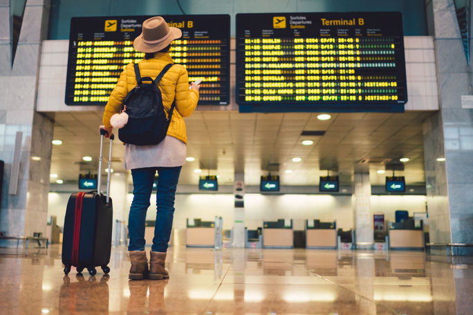 Young woman at airport checking flight departures