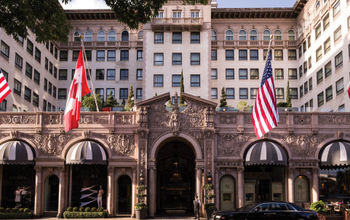 Hotel facade with flags and black house car
