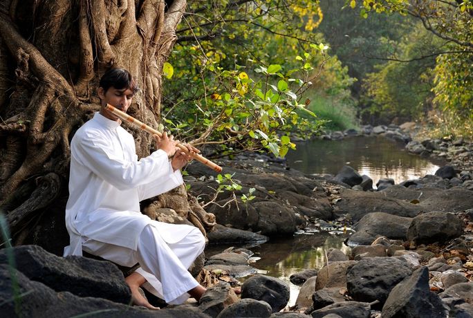 Flute player near a stream at Dharana wellness retreat, Shillim Valley, India. Dharana, wellness, retreats, resorts, Shillim Valley, India, flute, stream, meditation, mindfulness, zen