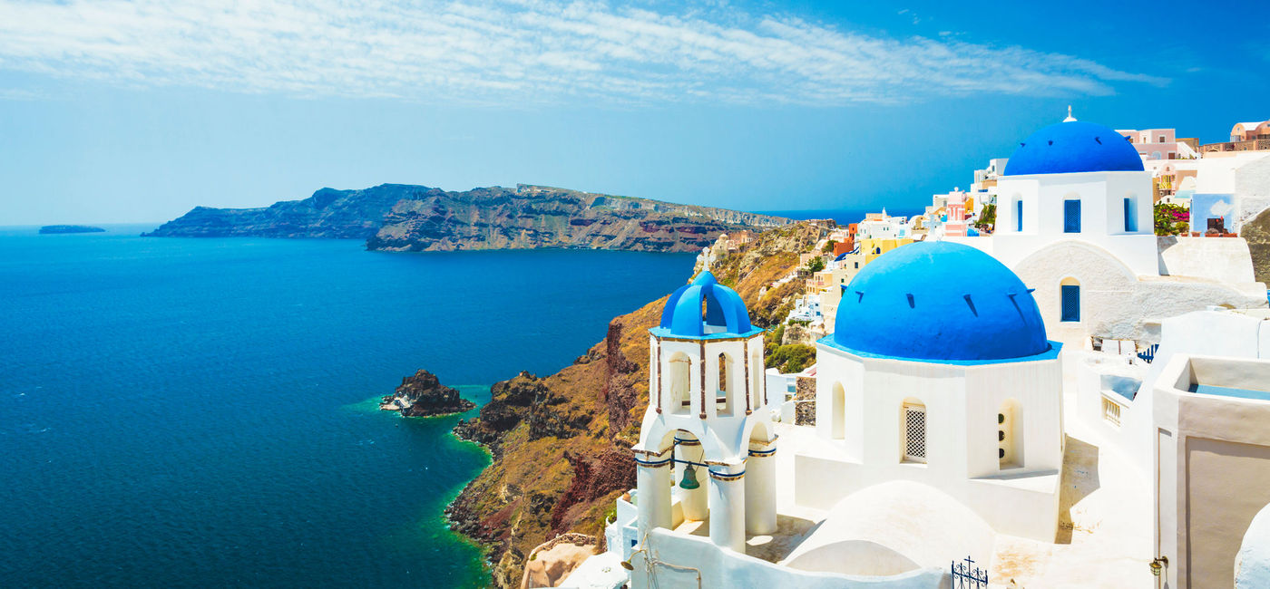 Image: Santorini's blue ocean matches the blue roofs of some of the white buildings. (photo via E+ / spooh) (E+ /  spooh)