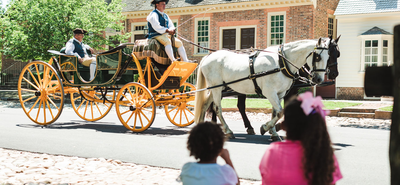 Image: Two girls watch a horse-drawn carriage pass by in Colonial Williamsburg. (photo via Colonial Williamsburg) ((photo via Colonial Williamsburg))