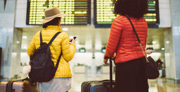 Tourists at the airport waiting for the flight to be announced on the arrival departure board