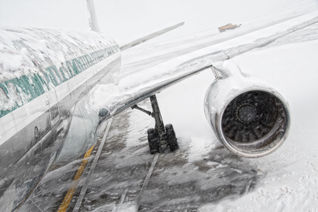 Airplane covered in snow and ice during a winter storm.