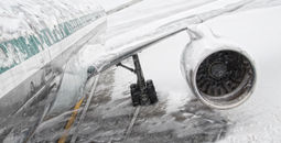 Airplane covered in snow and ice during a winter storm.