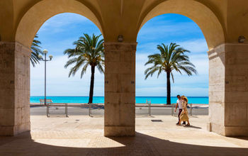 View of turquoise ocean and palm trees through masonry arches