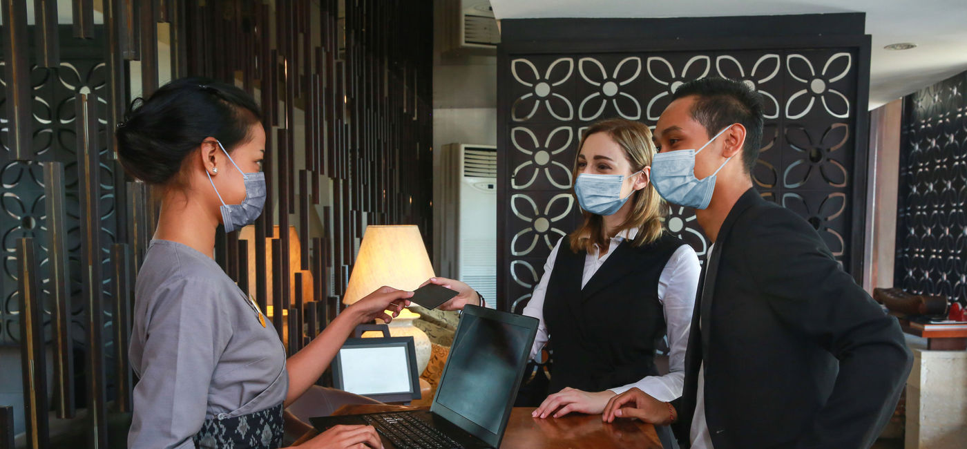 Image: A hotel worker checks in a couple. (Photo via iStock/Getty Images Plus/Space_Cat)