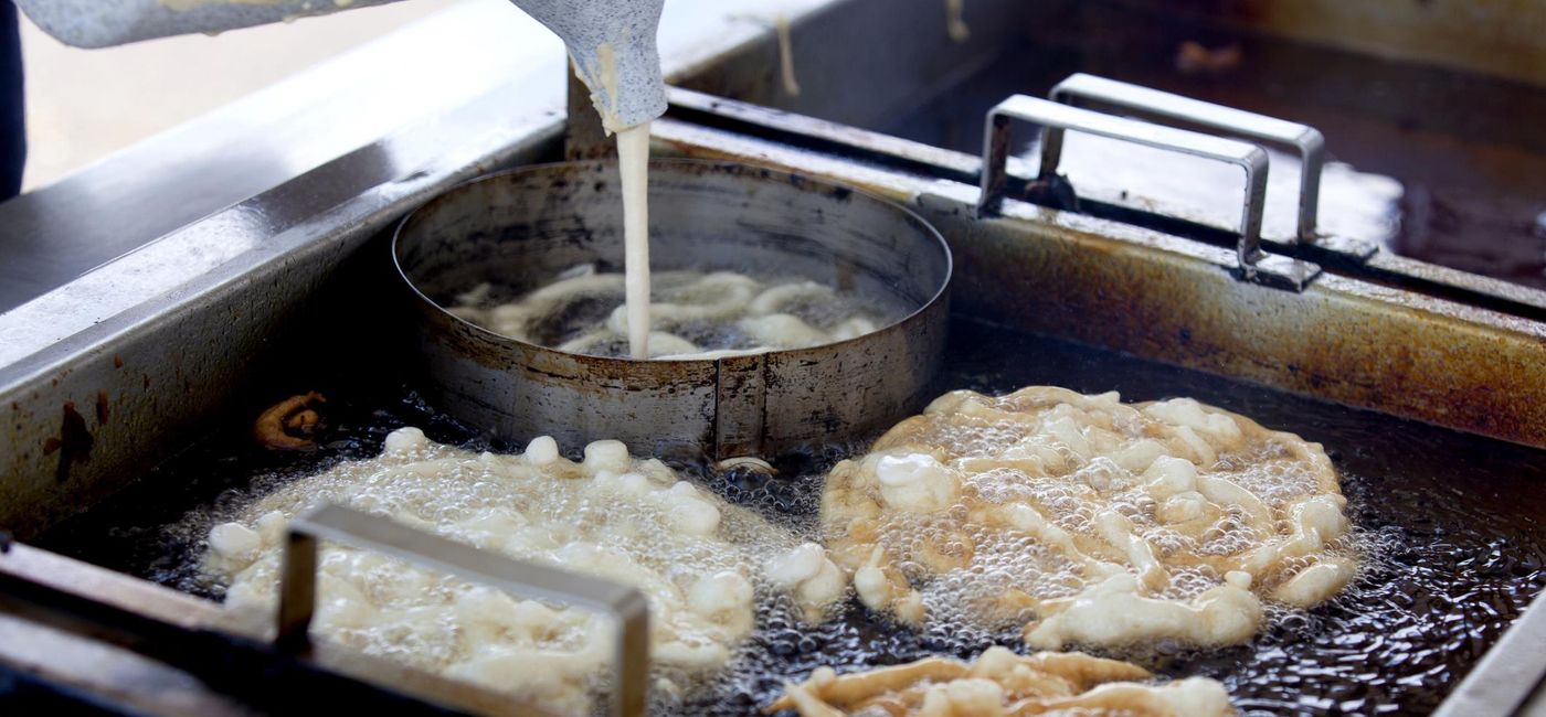 Image: PHOTO: A vender making funnel cakes at a state fair. (photo via Aneese/iStock/Getty Images Plus)