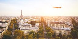 airplane flying over cityscape of Paris with Eiffel Tower (Photo via anyaberkut / iStock / Getty Images Plus)