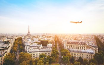 airplane flying over cityscape of Paris with Eiffel Tower (Photo via anyaberkut / iStock / Getty Images Plus)