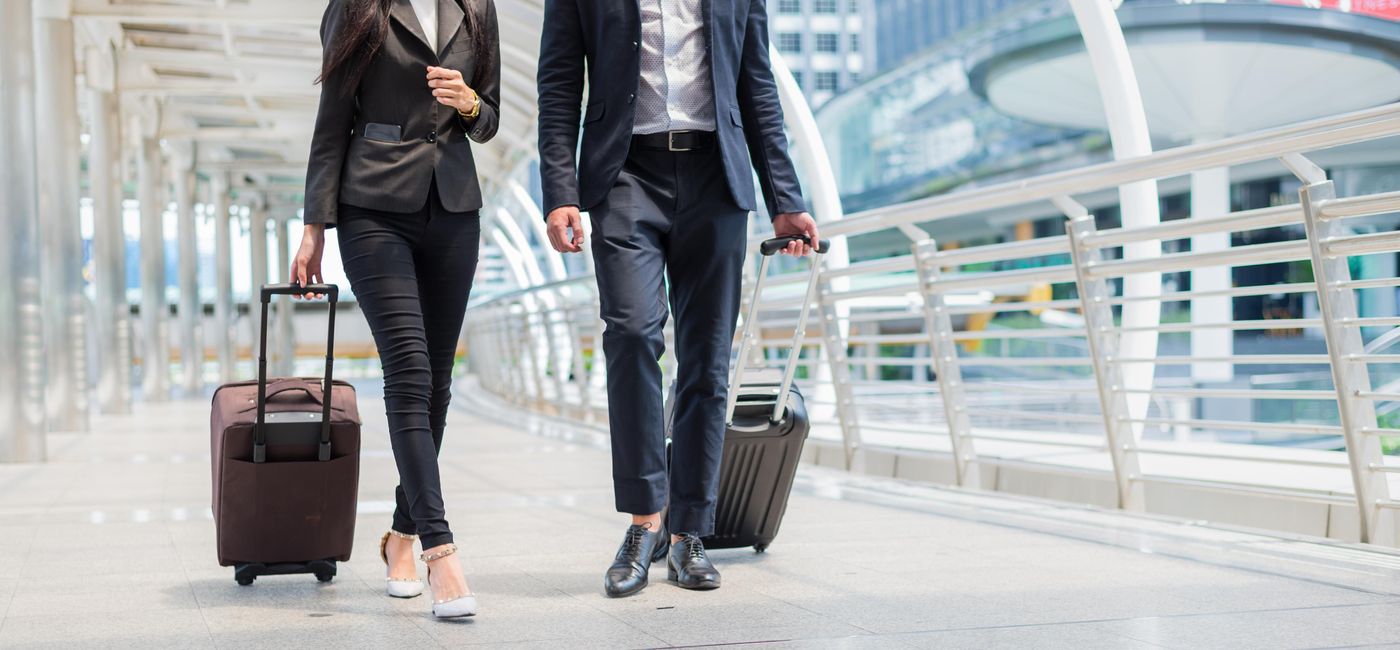Image: Business travelers walking together with luggage. (photo via Shuttermon/iStock/Getty Images Plus)