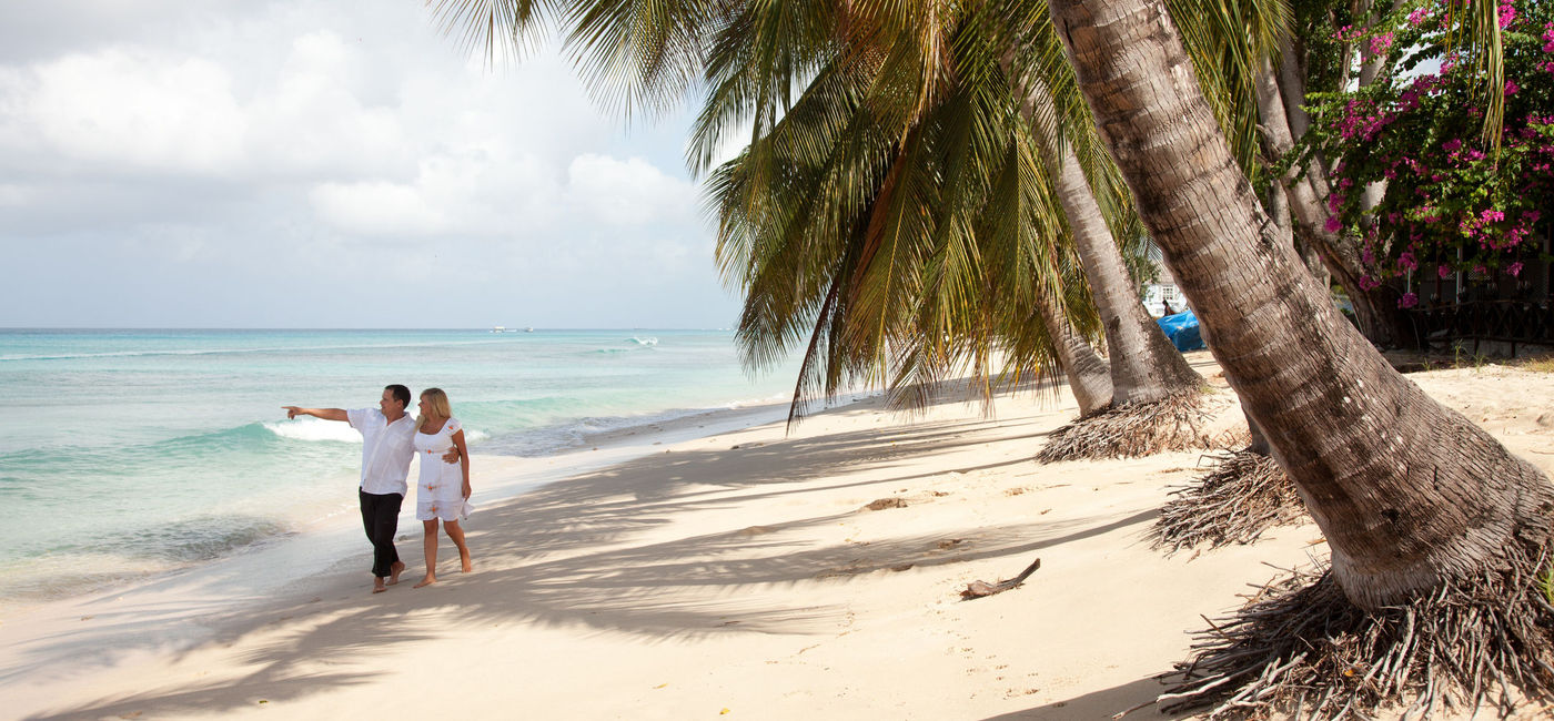 Image: Couple walking on the beach in Barbados. (photo via boophotography/iStock/Getty Images Plus)