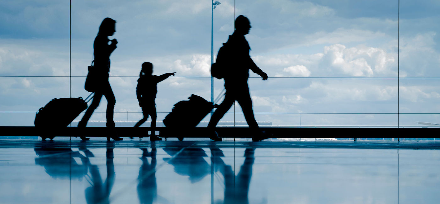 Image: Family at the airport. (photo via NicoElNino / iStock / Getty Images Plus)