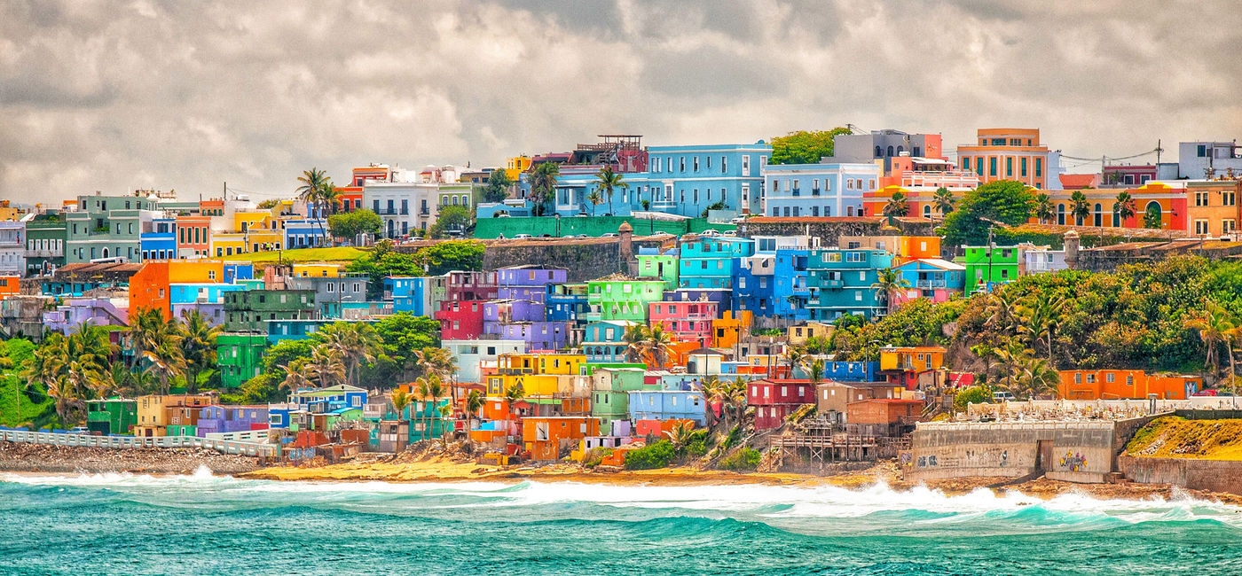 Image: Colorful stacked houses overlooking the sea in Puerto Rico. (photo via iStock/Getty Images Plus/Martin Wheeler)