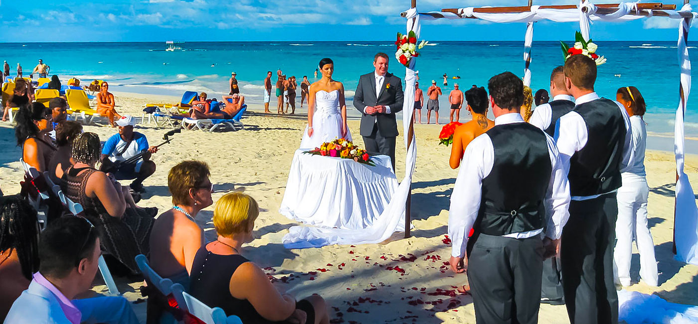 Image: A wedding ceremony takes place on a beach in the Dominican Republic. (photo via Marina113/iStock Editorial/Getty Images Plus)