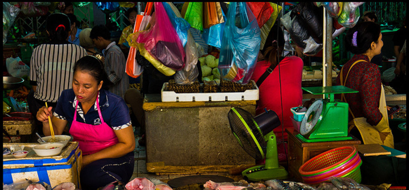Image: PHOTO: A fishmonger eats at her food stall in the Phnom Penh Central Market. (photo via Flickr/Guillén Pérez)