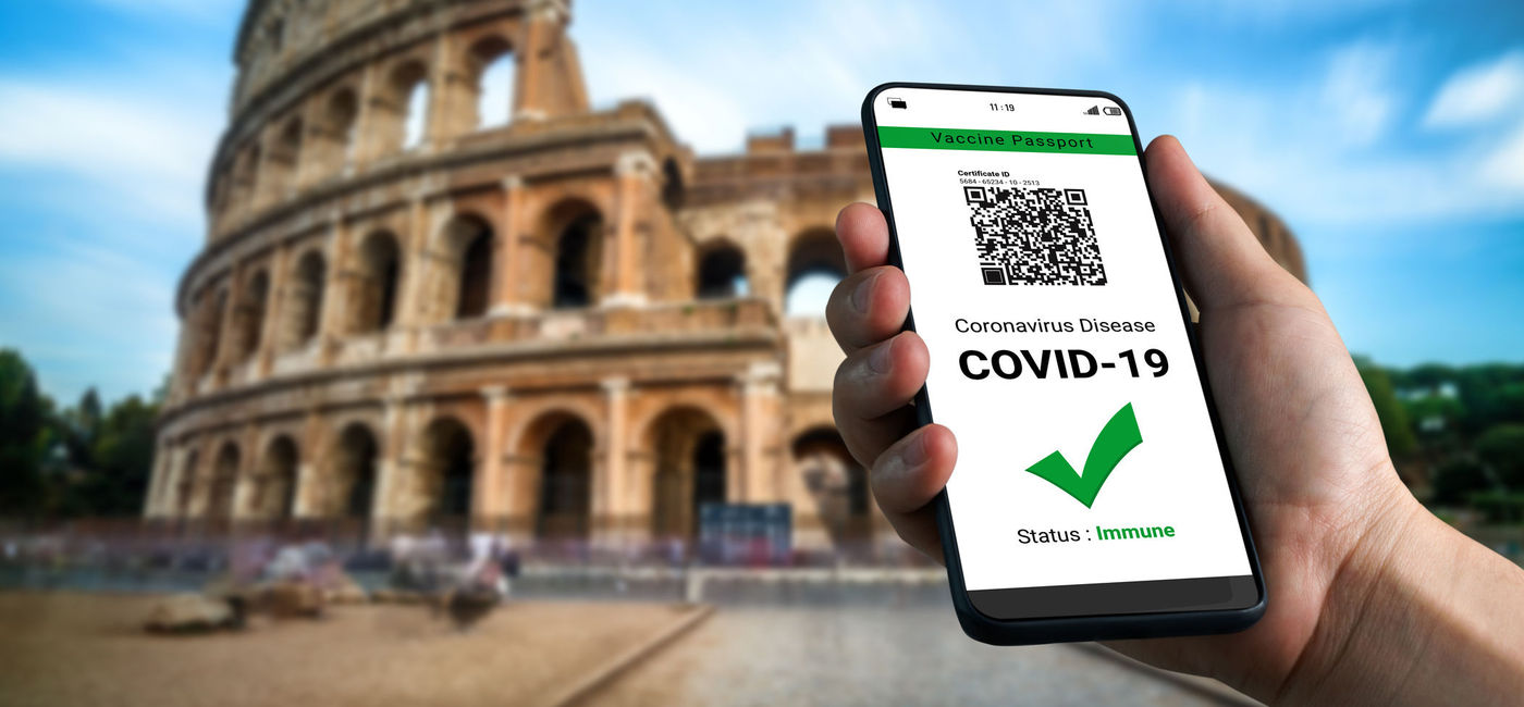 Image: Traveler holding a digital vaccine passport in front of Rome's Colosseum. (photo via iStock/Getty Images Plus/Fritz Jorgensen)