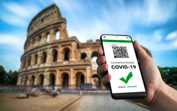 Traveler holding a digital vaccine passport in front of Rome's Colosseum.